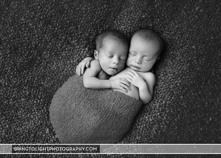 Newborn twins snuggled together in a wrap